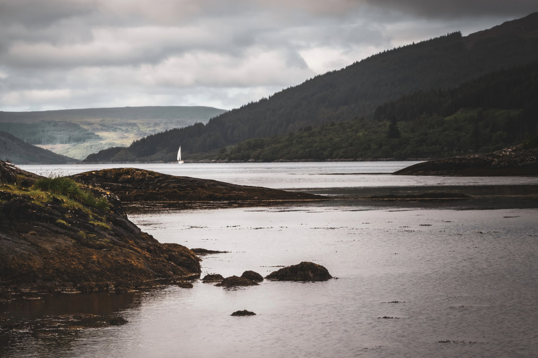A distant boat sailing down Loch Sunart and away from Salen on a grey and overcast day | Ardnamurchan, Scotland | Steven Marshall Photography